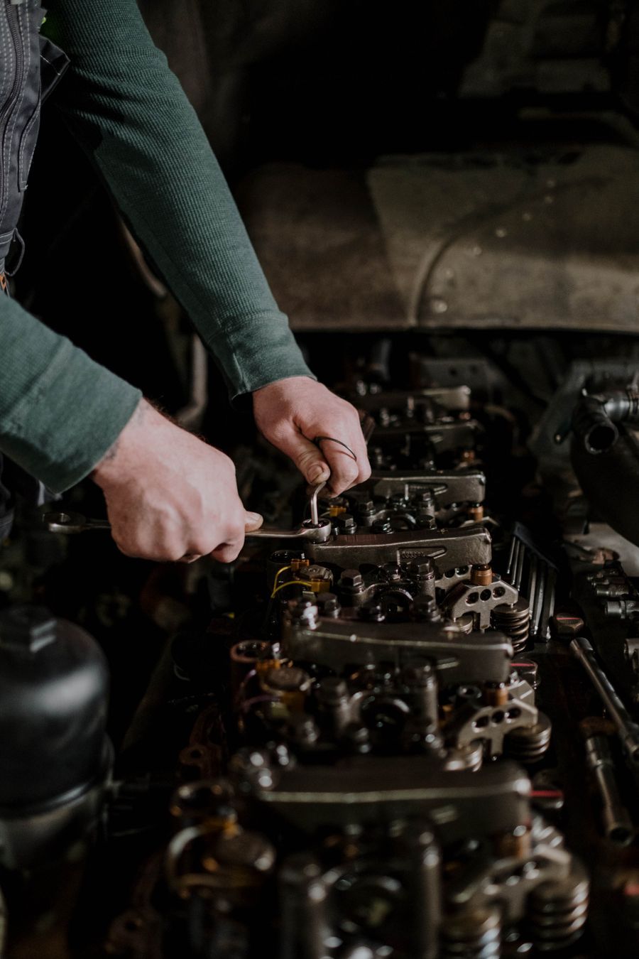 Mechanic's hands using a wrench on an engine